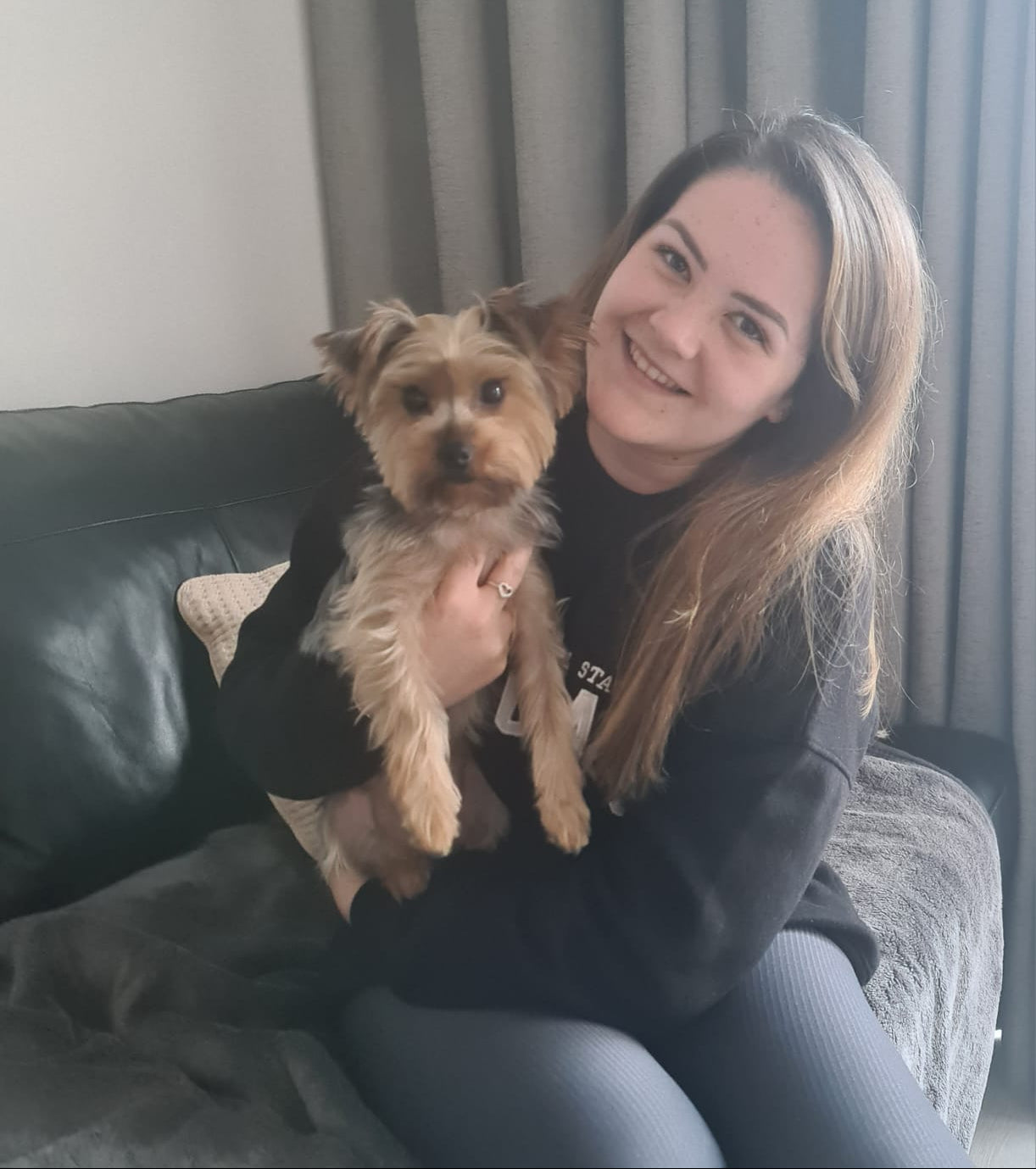 Woman holding a small dog in a living room setting